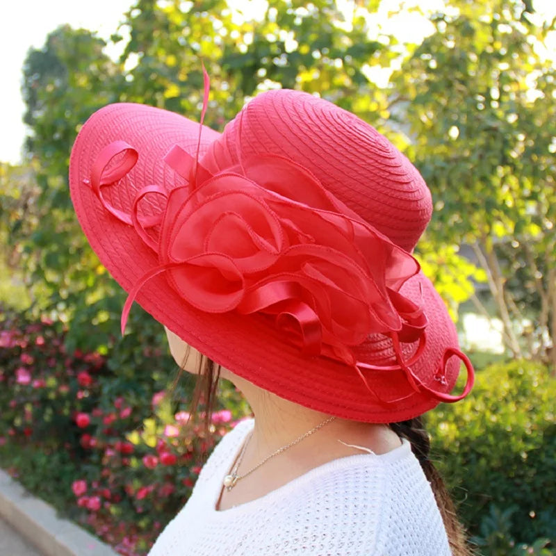 A bright red, wide-brimmed occasion hat adorned with large, structured floral ribbon detail.