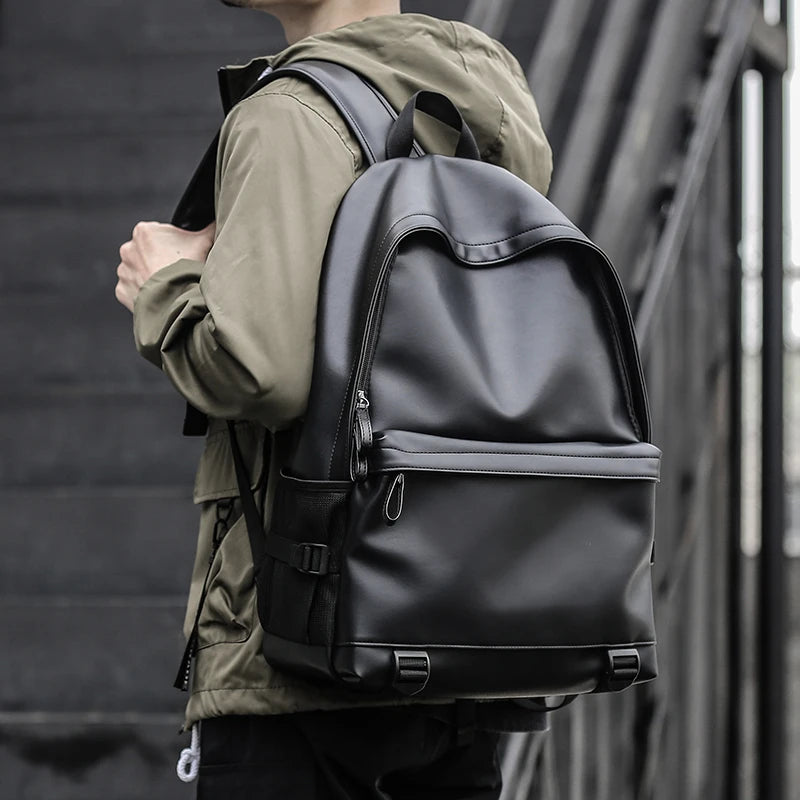 A sleek, black professional PU leather laptop backpack with a spacious main compartment and front zip pocket.