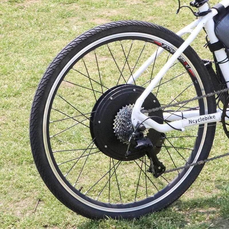 Black electric bike hub motor conversion kit installed on a bicycle wheel with silver gears and black spokes.