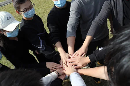 The product image provided does not feature a backpack; it shows a group of people stacking their hands together.
