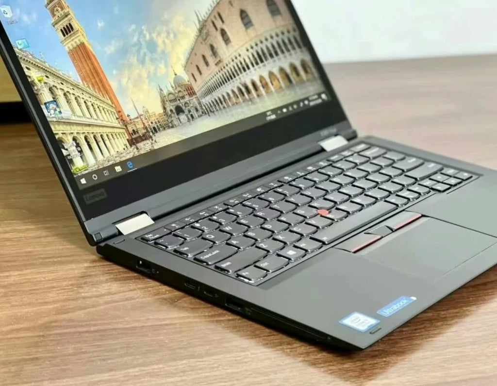 Sleek 13.3-inch black 2-in-1 business laptop with touchscreen, showing a landscape wallpaper on a wooden desk.