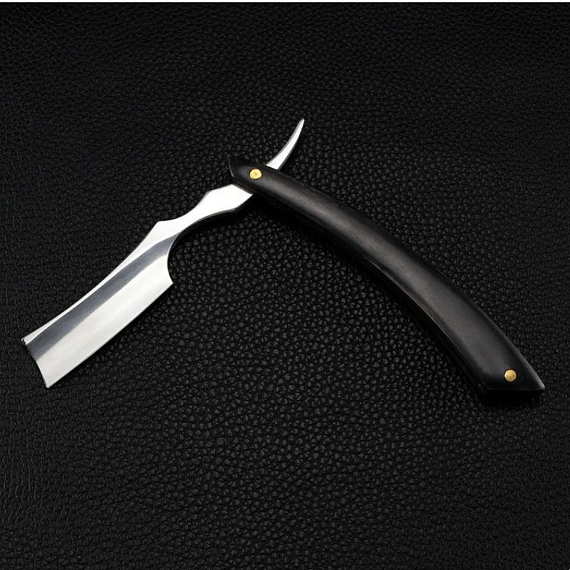 Professional stainless steel straight razor with a curved black handle and gold-toned rivets on a black leather texture.