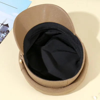 Tan faux leather peaked beret hat with a black interior lining and gold side detail.