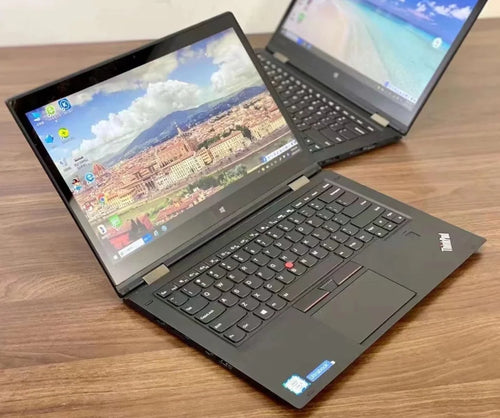 Two sleek black 13.3-inch 2-in-1 touchscreen business laptops angled on a wooden desk.