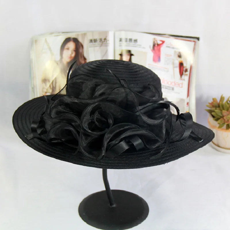 Elegant black occasion hat featuring a wide brim and decorative organza floral detailing.