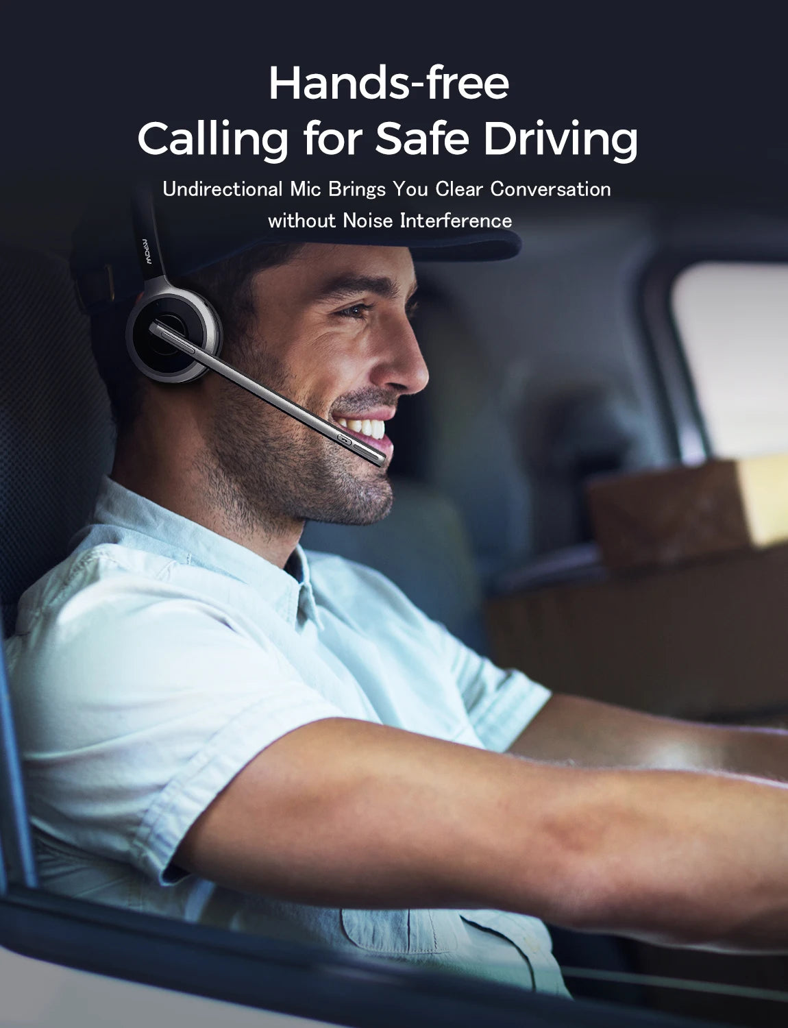 A man driving a vehicle wearing a sleek, black and silver wireless headset with a long, adjustable microphone boom.
