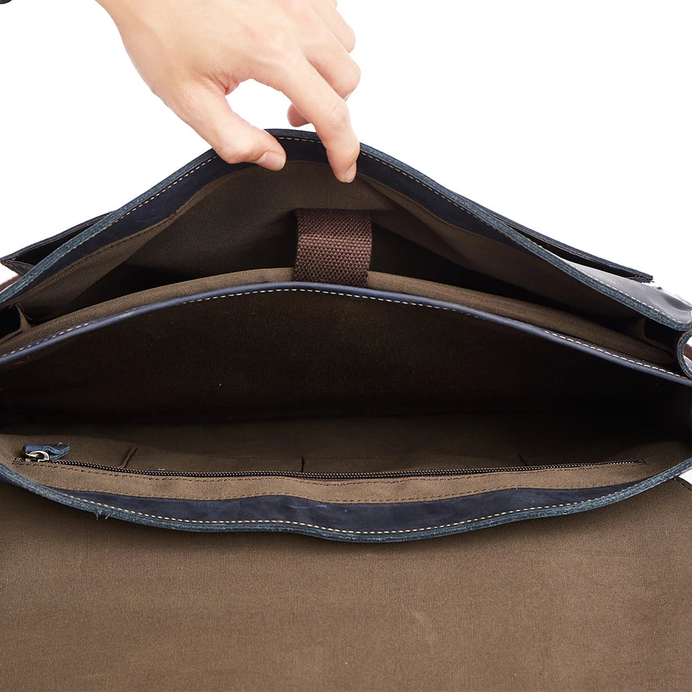 Open navy blue leather satchel showing a brown fabric-lined interior, laptop compartment, and secure zip pocket.