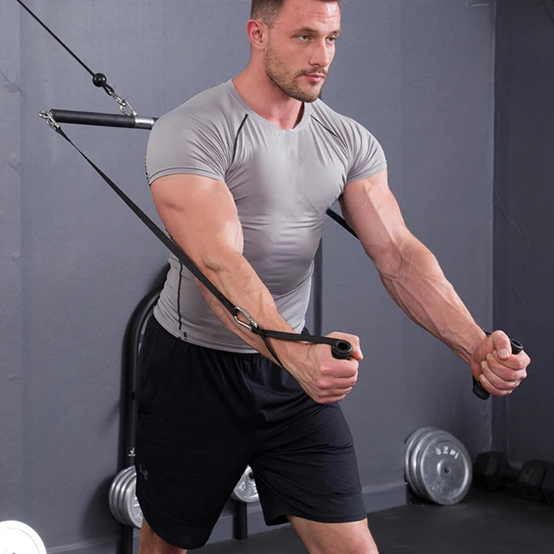 A man in a grey t-shirt and black shorts uses resistance bands with handles for an upper body exercise.