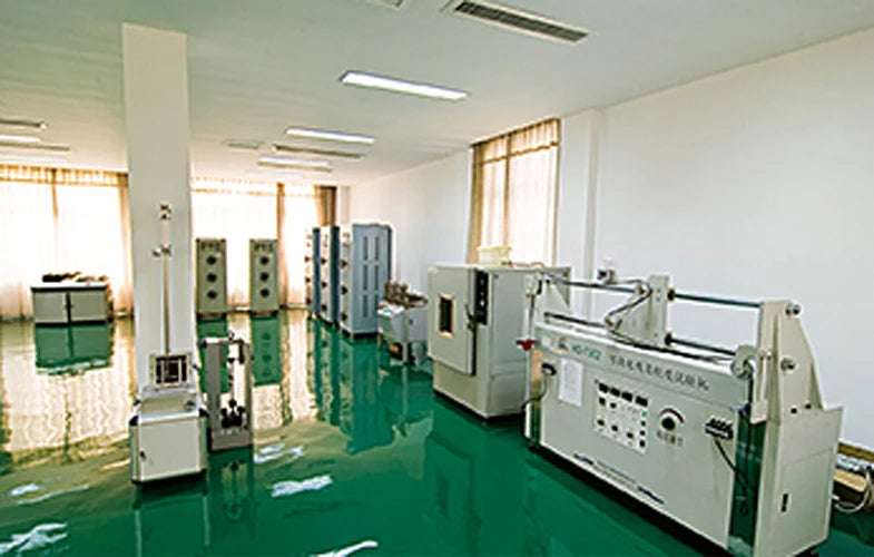 The image shows a professional manufacturing facility with industrial testing equipment on a green floor.