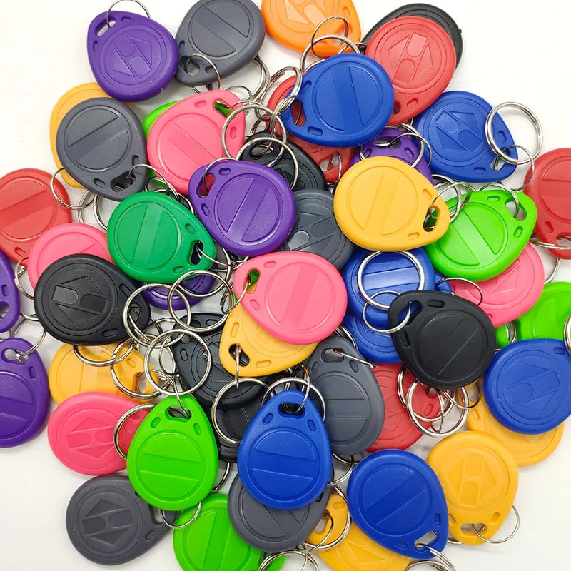 A pile of colorful plastic RFID key fob tags, each with a metal split ring, in various bright colors.