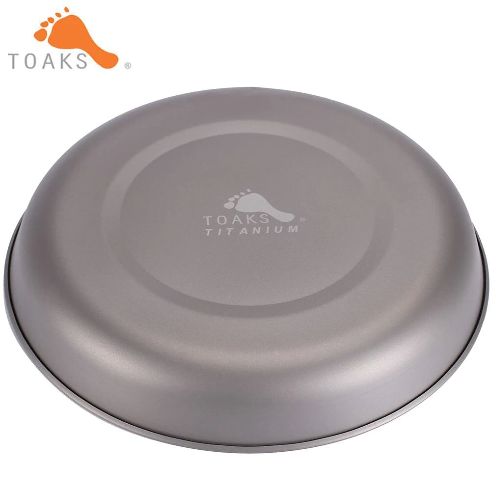TOAKS Titanium plate viewed from the top, featuring a round, shallow grey metal dish with a brand logo printed inside.