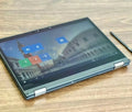 Sleek charcoal grey 13.3-inch 2-in-1 touchscreen business laptop folded flat, including a stylus on a wooden desk.