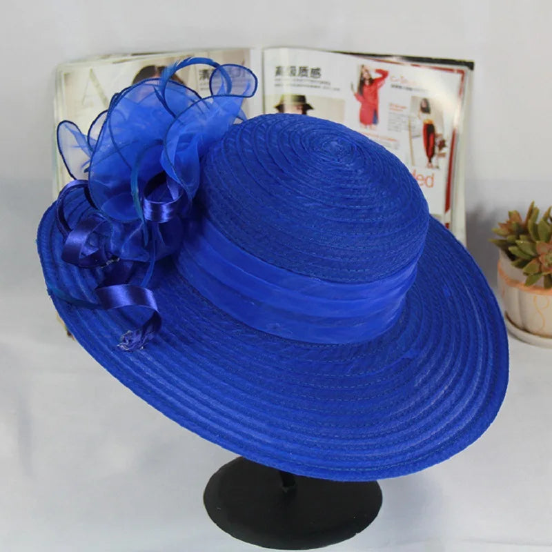 Elegant royal blue wide-brim occasion hat featuring a textured finish and a large, decorative organza floral accent.