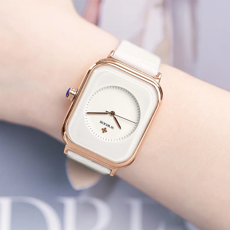 Elegant ladies' square watch with a rose gold case, white dial, and white leather strap on a wrist.