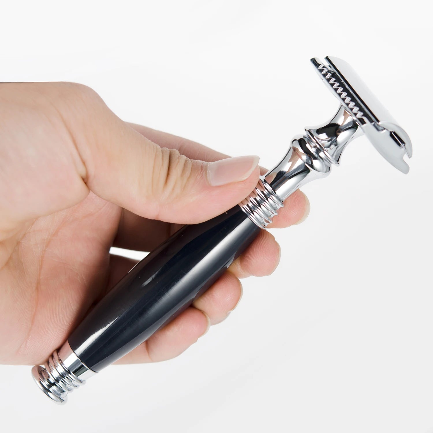 A hand holding a traditional double-edged safety razor with a shiny chrome head and a sleek black handle.