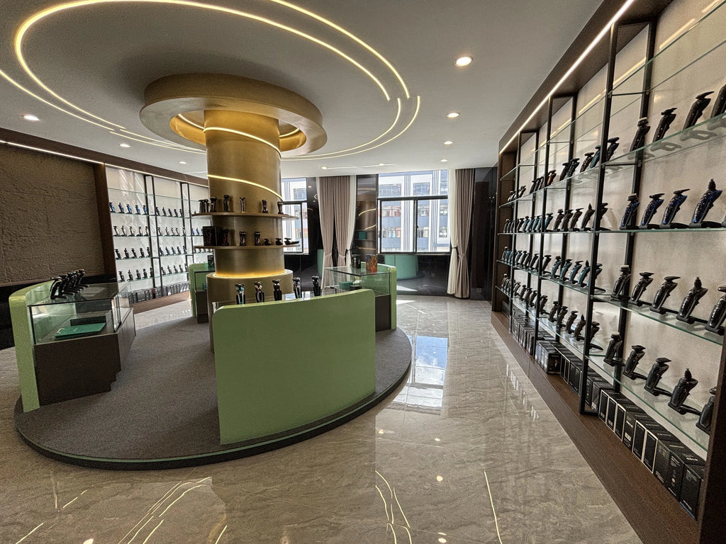 A bright showroom displaying rows of black rechargeable electric hair trimmers on glass shelves and a central green desk.
