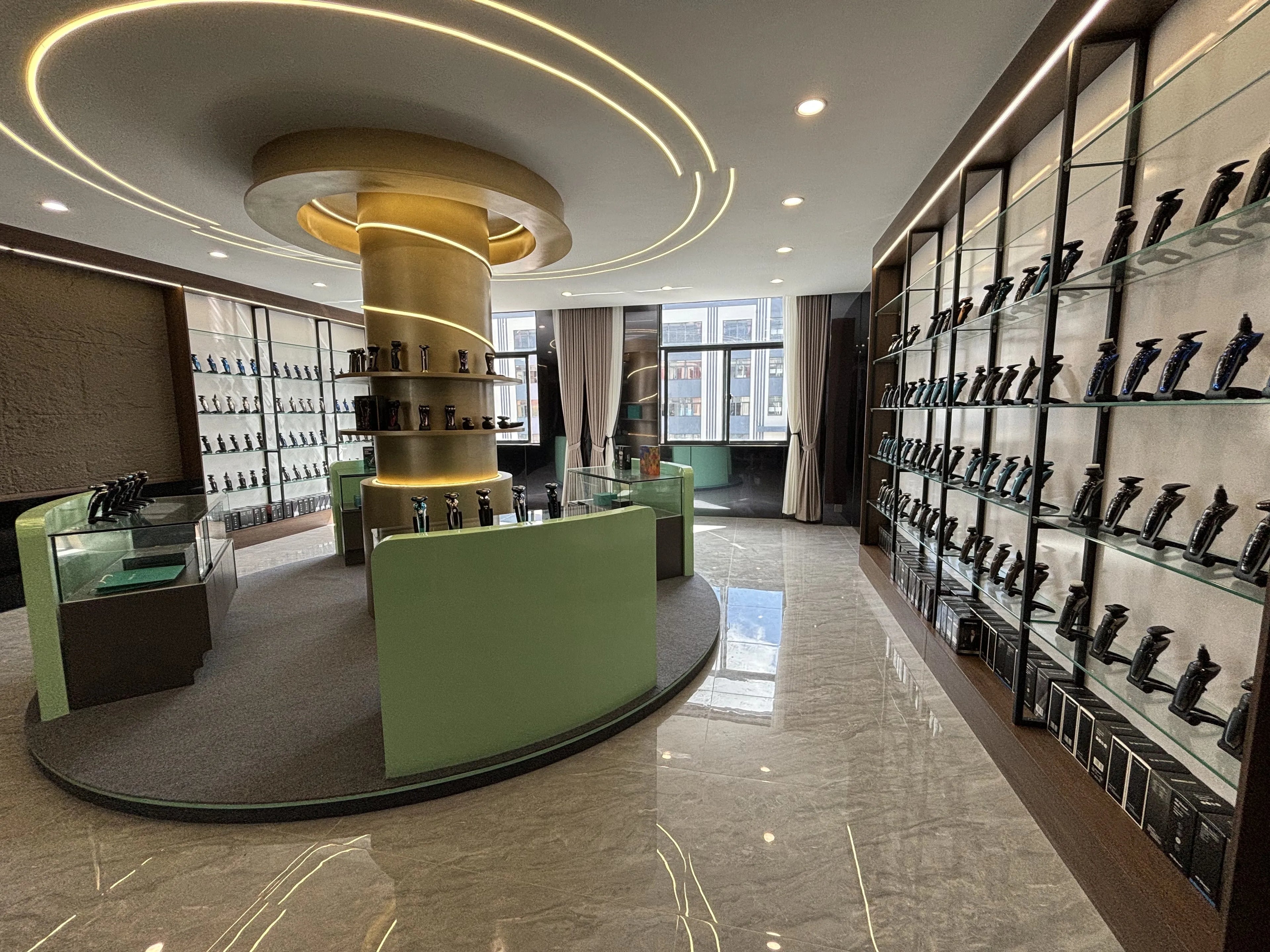 A bright showroom displaying rows of black rechargeable electric hair trimmers on glass shelves and a central green desk.
