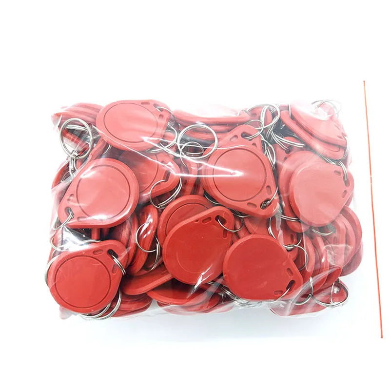 A plastic bag filled with many round, red plastic RFID key fob tags, each attached to a metal split key ring.