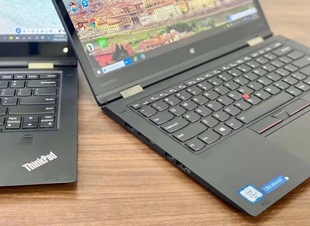 A sleek black 13.3-inch 2-in-1 business touchscreen laptop with a backlit keyboard on a wooden desk.
