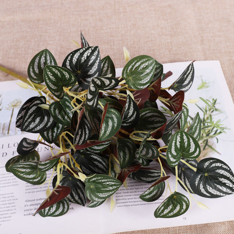 Artificial plant spray with dark green, heart-shaped leaves featuring striking white variegated vein patterns.