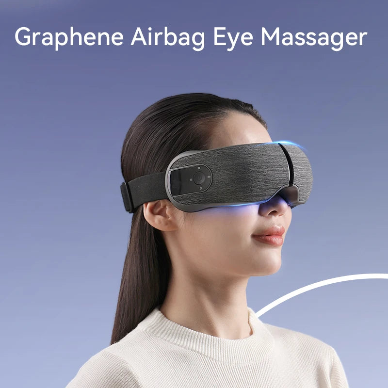 Person wearing a grey, fabric-covered smart eye compression massager with built-in music and heat functions.