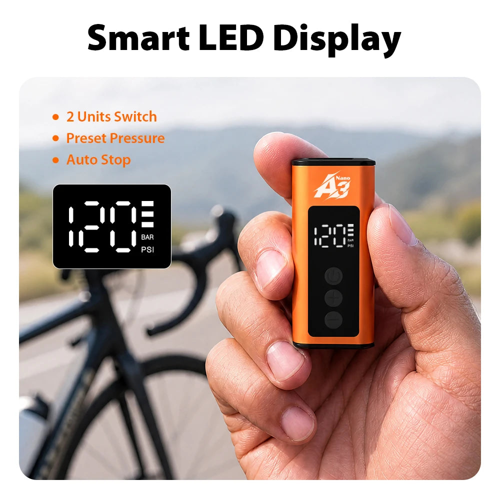 Hand holding orange portable electric bike air compressor with smart LED digital display and control buttons.