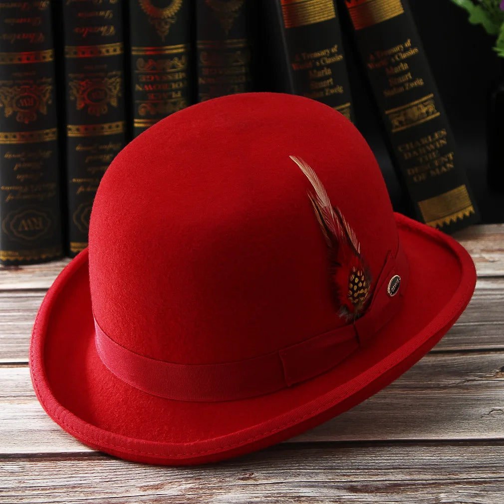 A classic red wool bowler hat with a matching ribbon band and a decorative side feather, set on a wooden surface.