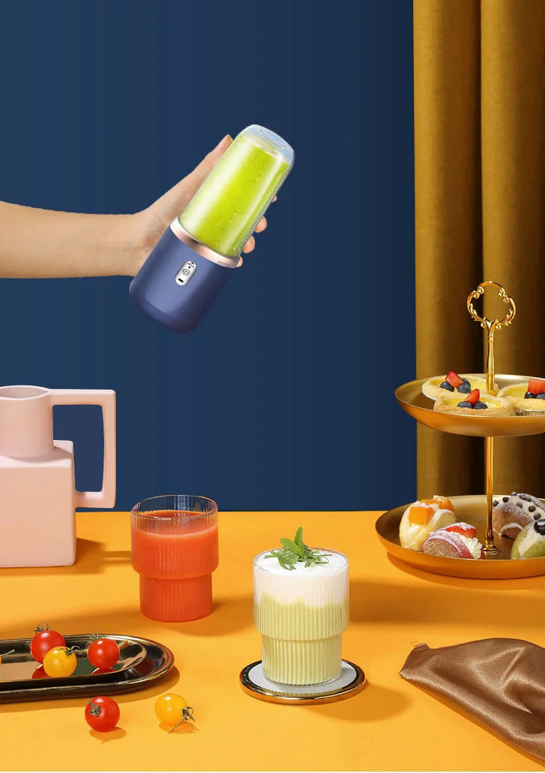 Handheld navy blue portable blender with a green smoothie inside, set against a vibrant yellow and blue background.
