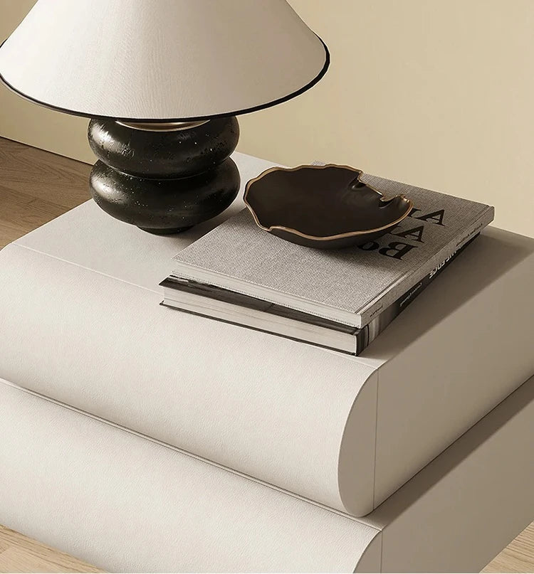A modern, cream-coloured floating bedside table featuring a smooth, curved design with two stacked drawers.