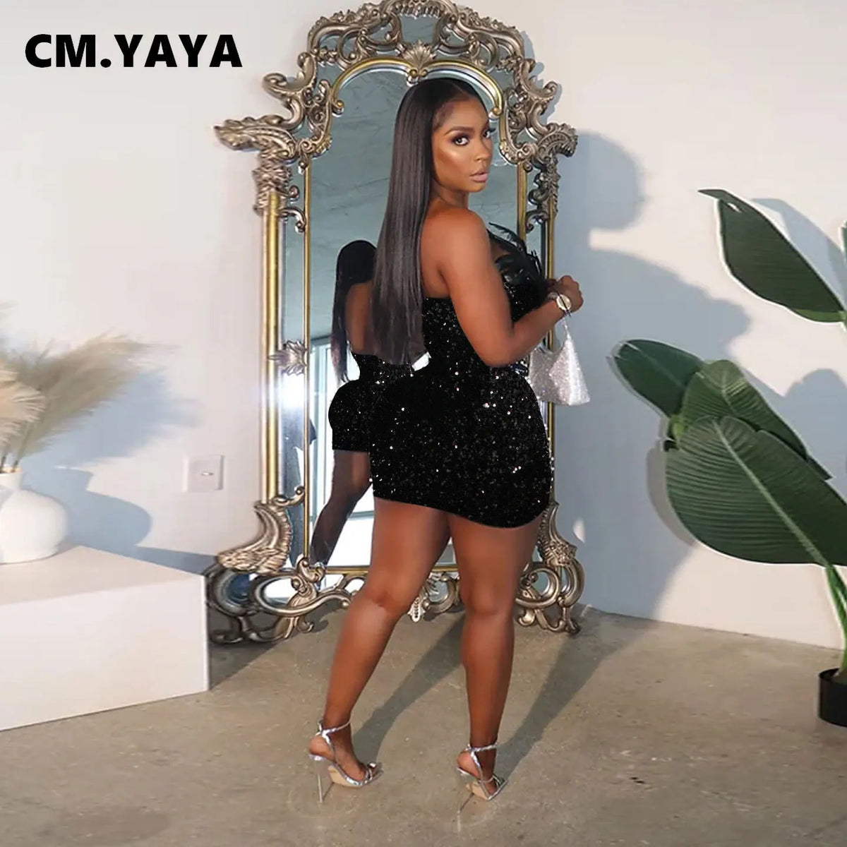 Black sequin strapless bodycon mini dress with feather trim, worn with silver heels.