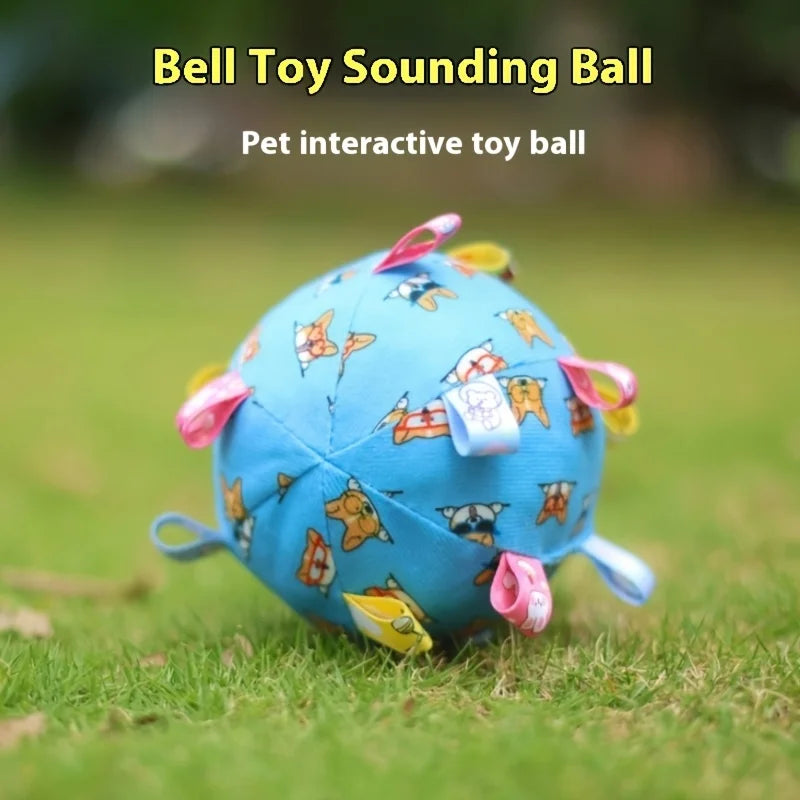 Light blue fleece dog ball with a cute animal pattern and colourful fabric loop tabs, resting on green grass.