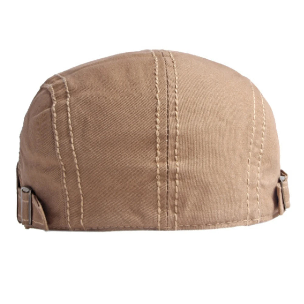 Tan cotton flat cap with decorative vertical stitching and adjustable side buckles.