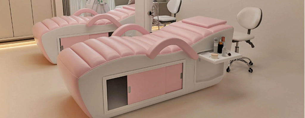 Professional pink and white massage bed featuring integrated storage cupboards and a slide-out side tray.