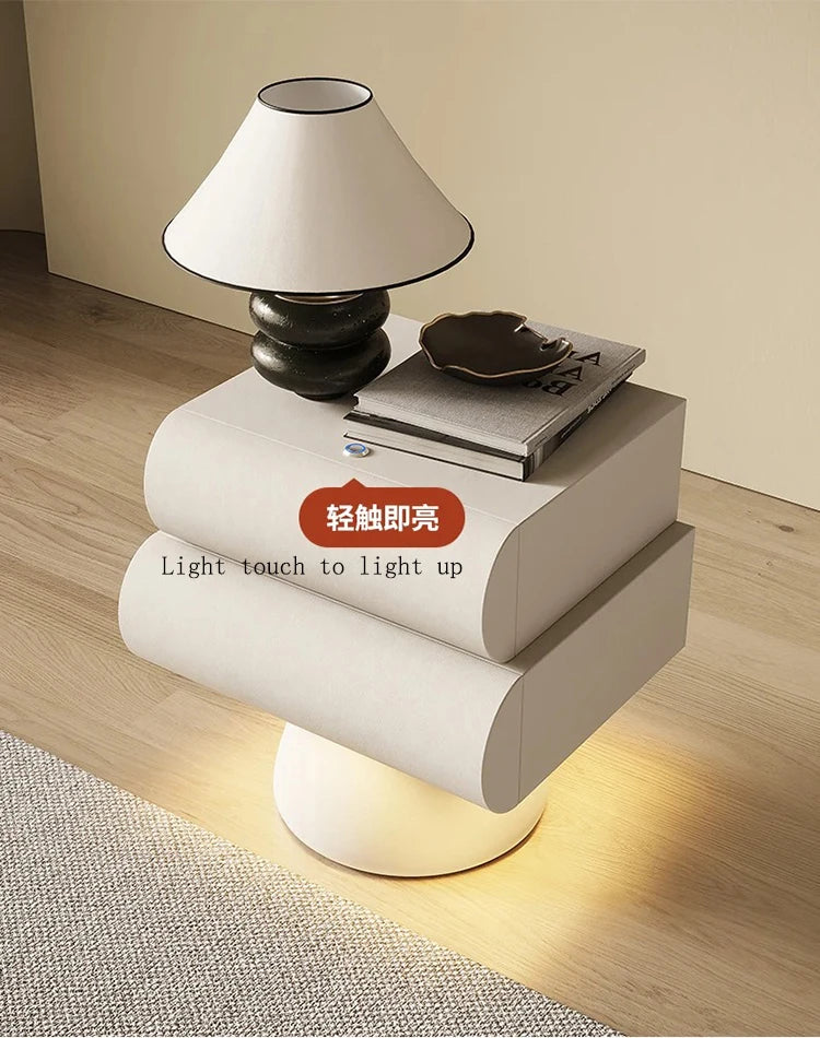 Modern, off-white floating bedside table with two drawers and integrated base lighting, styled with a desk lamp.