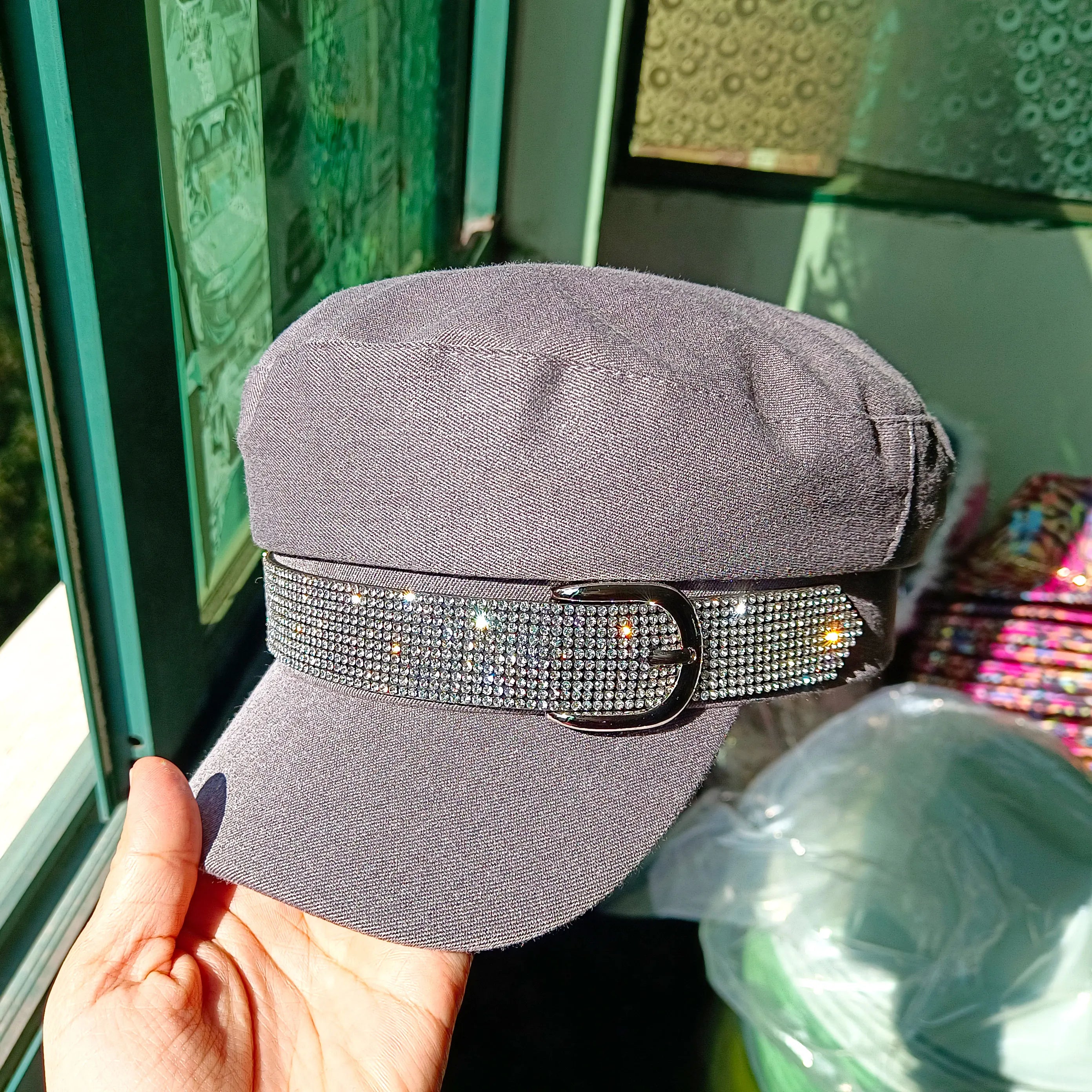 Grey baker boy hat featuring a sparkly rhinestone-embellished strap and a metallic buckle detail.