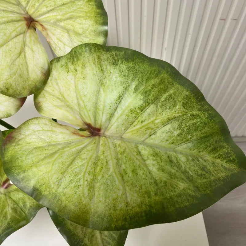 Artificial lotus leaves with light green centers, dark green edges, and delicate red veining at the stems.