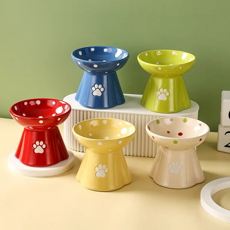 Five colourful, elevated ceramic cat bowls with polka dot patterns and white paw print detailing.