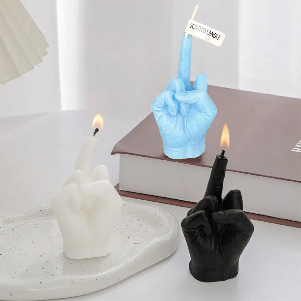 Three hand-shaped scented candles in white, black, and light blue, each showing a middle finger gesture.