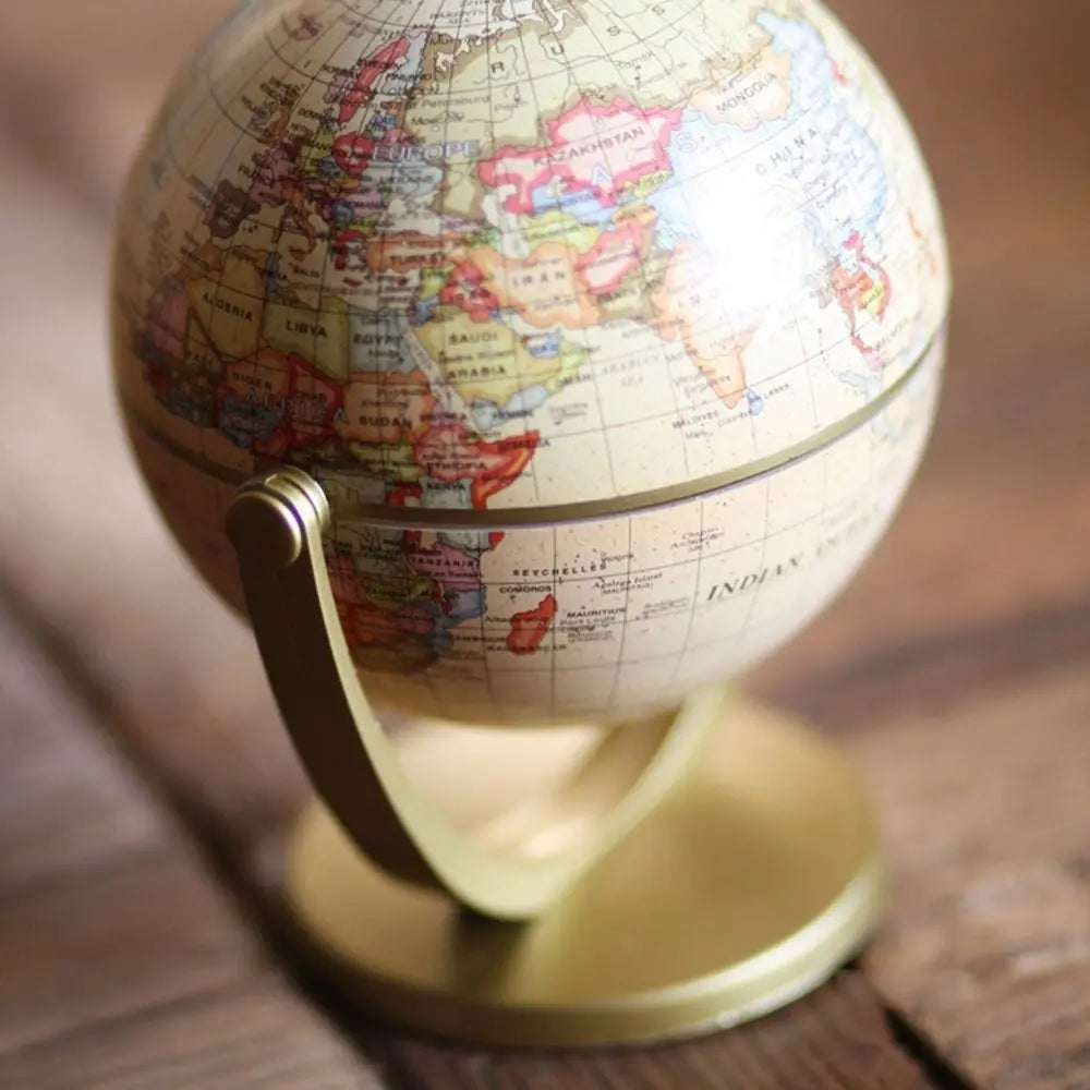 Vintage-style decorative world globe with muted colours on a sleek, matte gold metal stand and base.