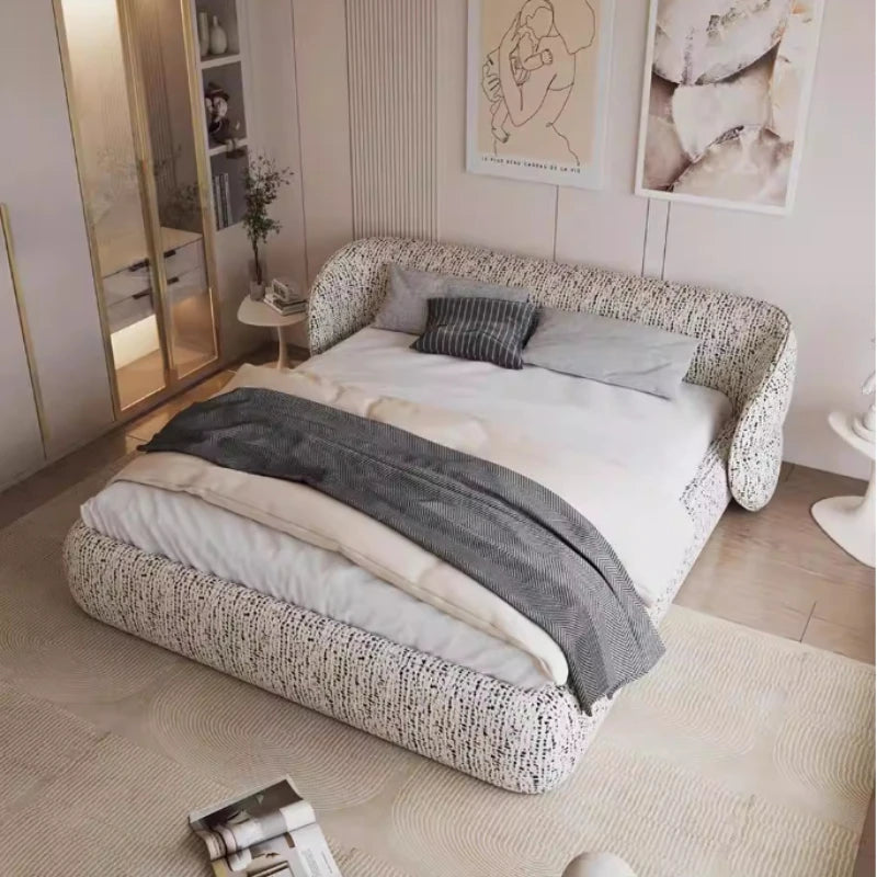 Modern bed frame in a textured cream and black fabric with a curved, wraparound headboard and low-profile base.
