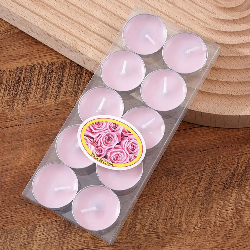 Pack of ten light pink rose-scented tea light candles in clear packaging, resting on a wooden surface.