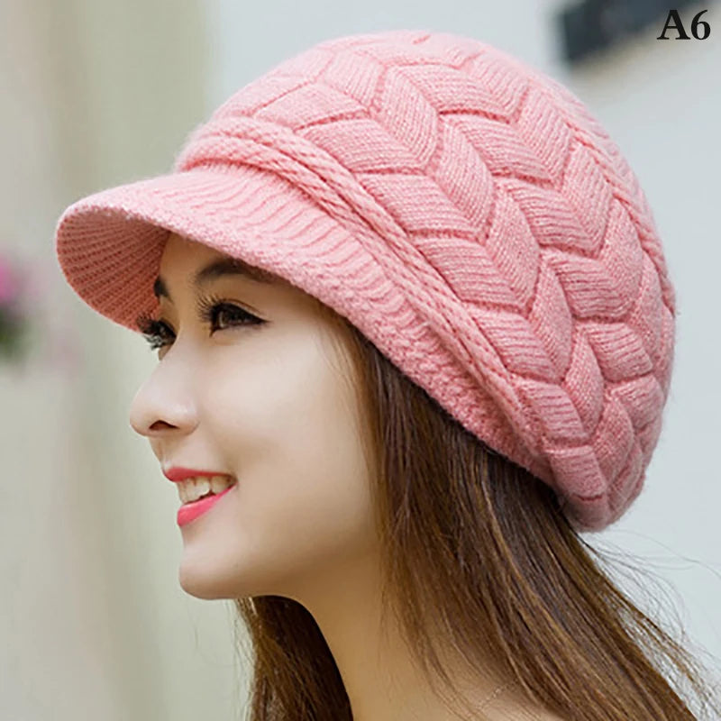 A woman wearing a cosy, pink knitted winter hat with a structured brim and chevron-patterned texture.