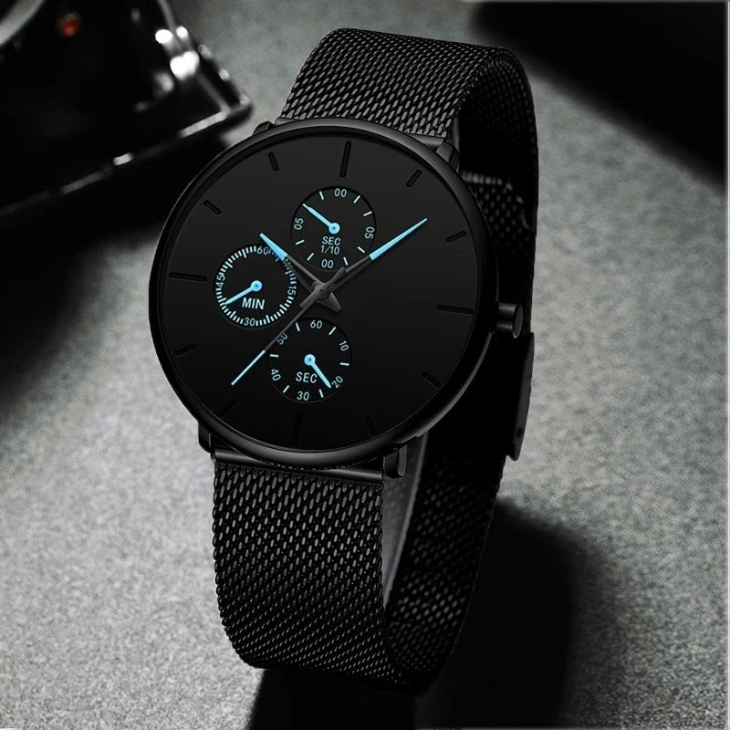 Ultra-thin men’s watch with a black stainless steel mesh strap, matte black dial, and glowing light blue hands.