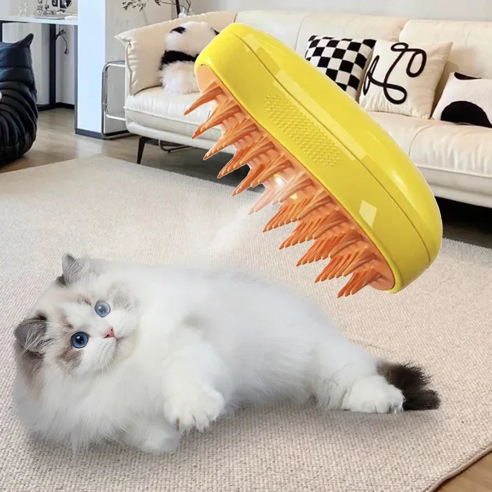 A yellow handheld pet grooming brush with orange silicone bristles hovering above a fluffy white cat on a rug.