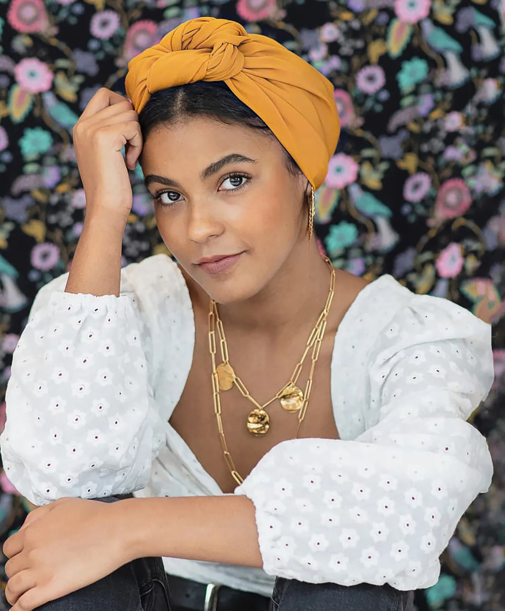 A model wearing a mustard yellow vintage-style knotted turban hat.