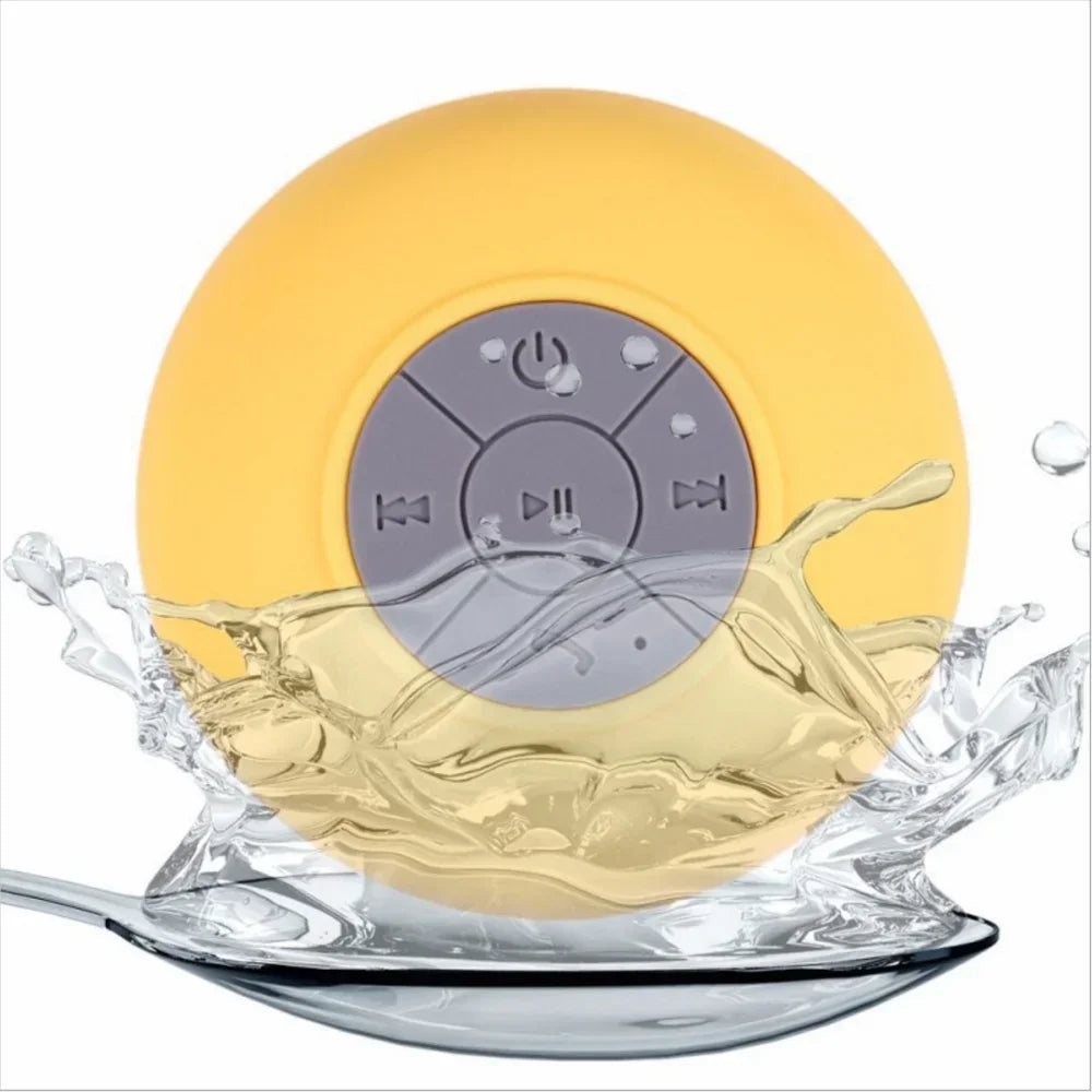 Yellow, round, waterproof Bluetooth speaker with a grey control panel, shown splashing in water.