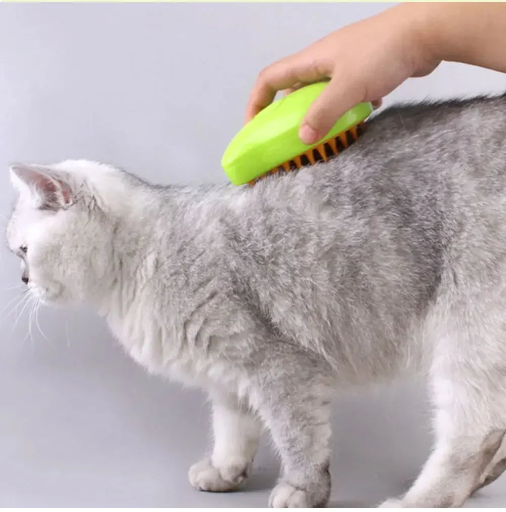 A person uses a bright lime-green electric steamy grooming brush to groom a fluffy grey cat.