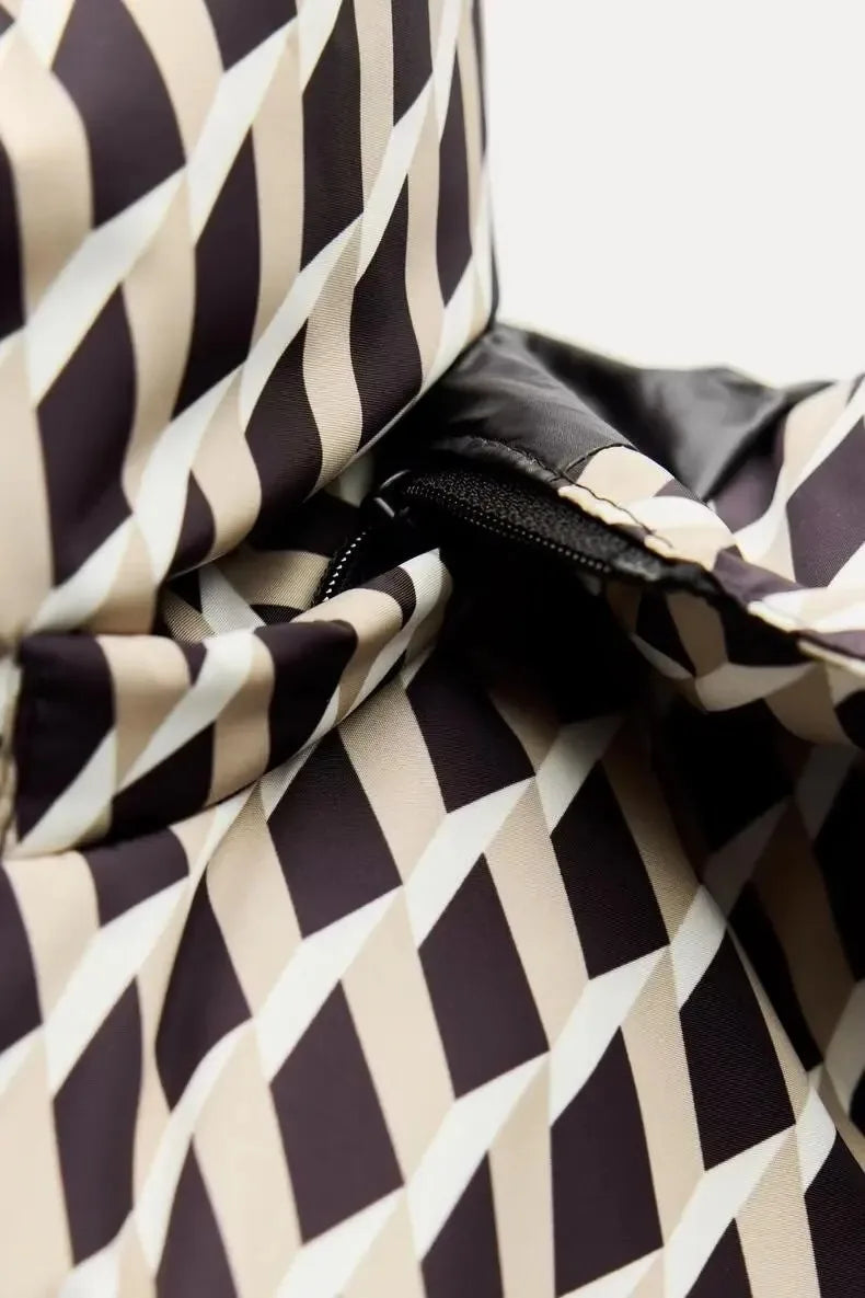 Close-up of a puffer jacket with a black, beige, and white geometric chevron pattern and a black zip detail.