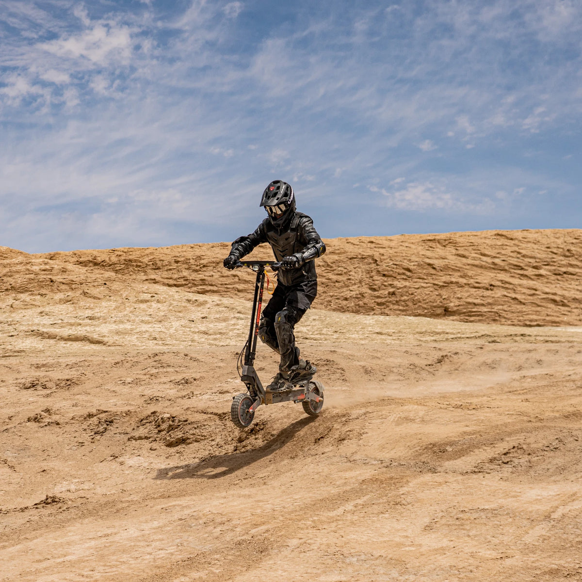 Black KuKirin G2 Ultra electric scooter with 10-inch tires ridden by a person in protective gear off-road.