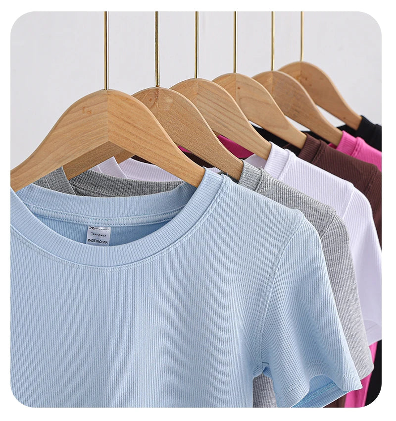 Selection of short-sleeved, crew-neck ribbed T-shirts in various colours hanging on wooden hangers.